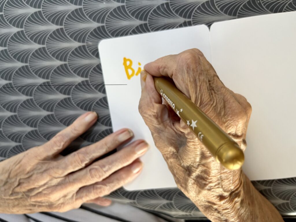 Mains d'une personne agée touchée par la maladie d'alzheimer et qui tente d'écrire